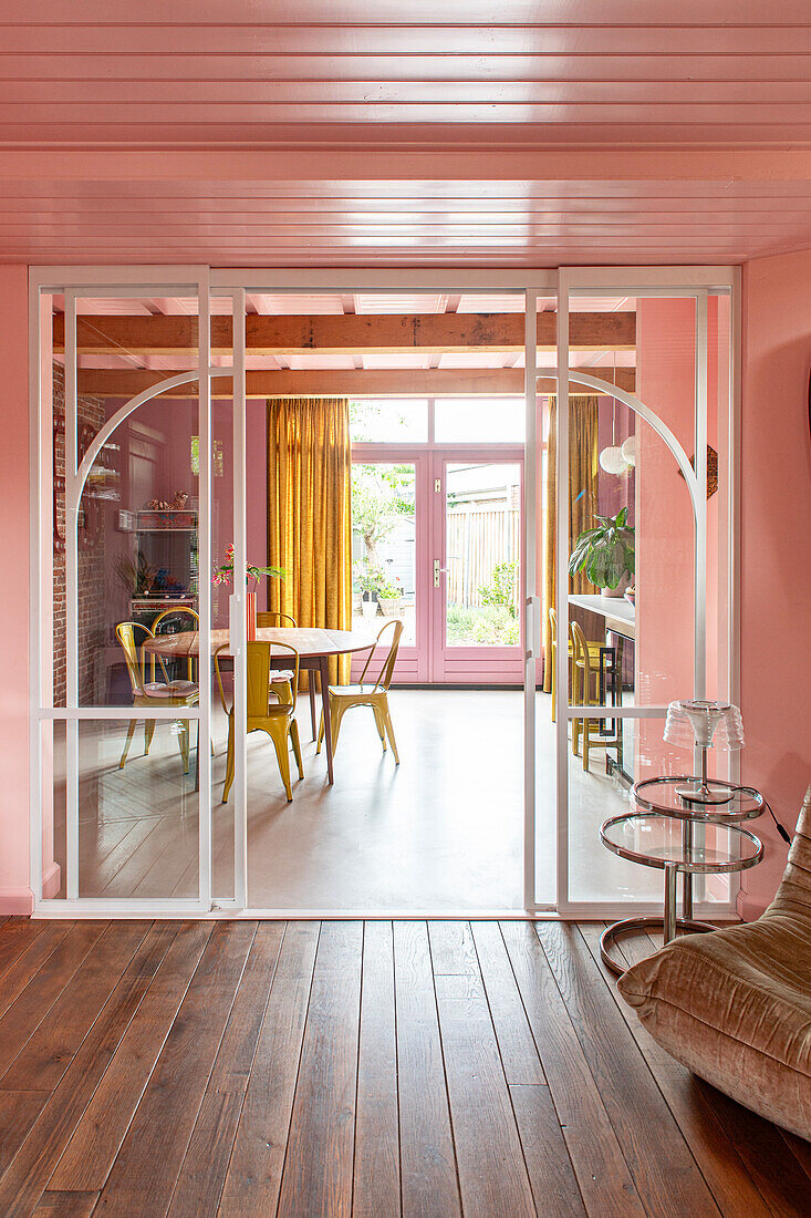 Open-plan living area with pink-painted walls and a view of the dining area