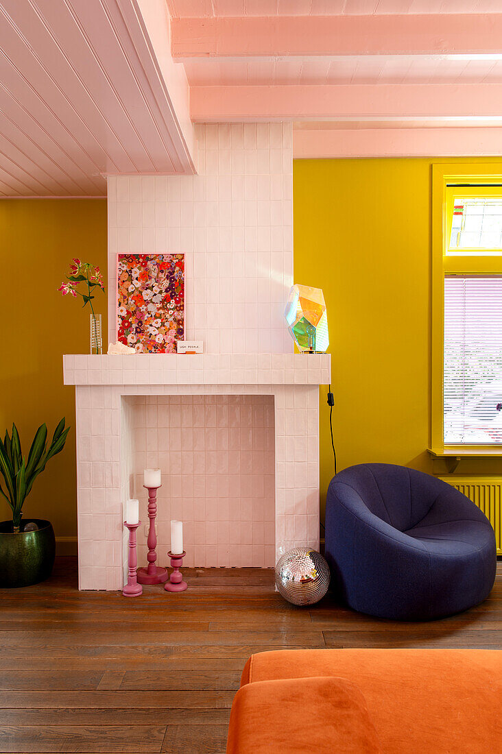 Fireplace area with white tiles, colourful accessories and upholstered blue armchair