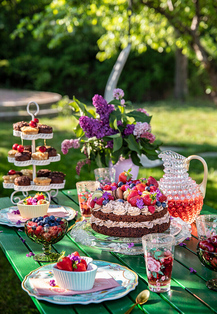 Gedeckter Tisch mit Torte, Obstschalen und Blumenstrauß
