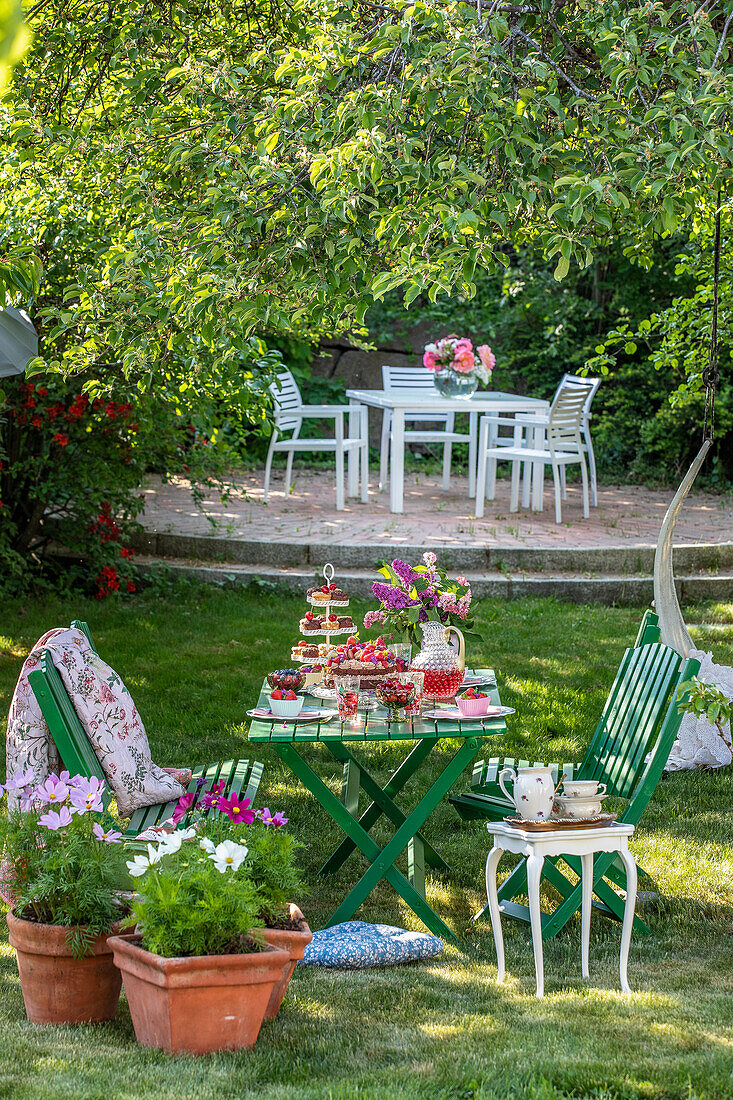 Garden idyll with coffee table and flowering potted plants