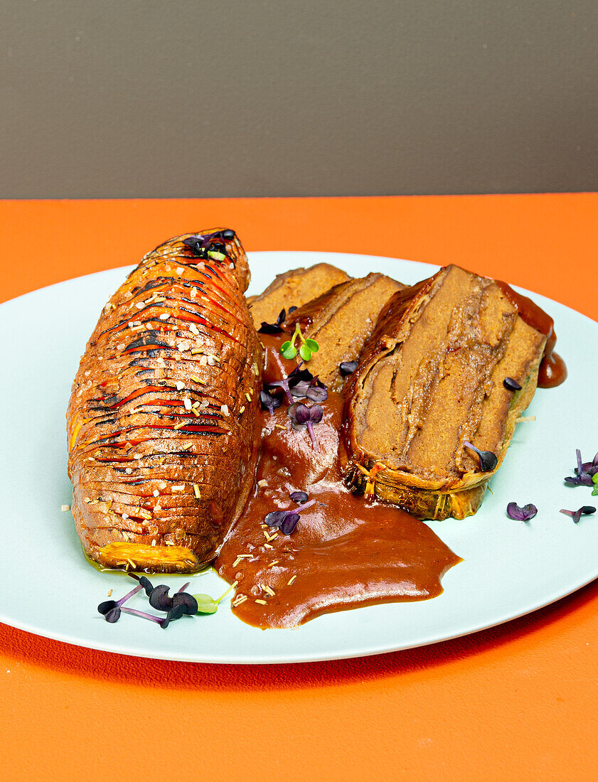 Layered roast (made from vegan meat substitute) with braising sauce and Hasselback sweet potatoes