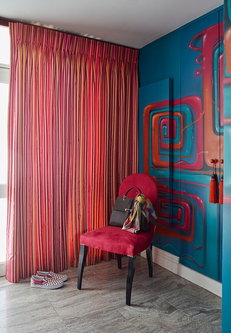 Handbag on chair with striped curtains and painted wardrobe in London apartment, UK