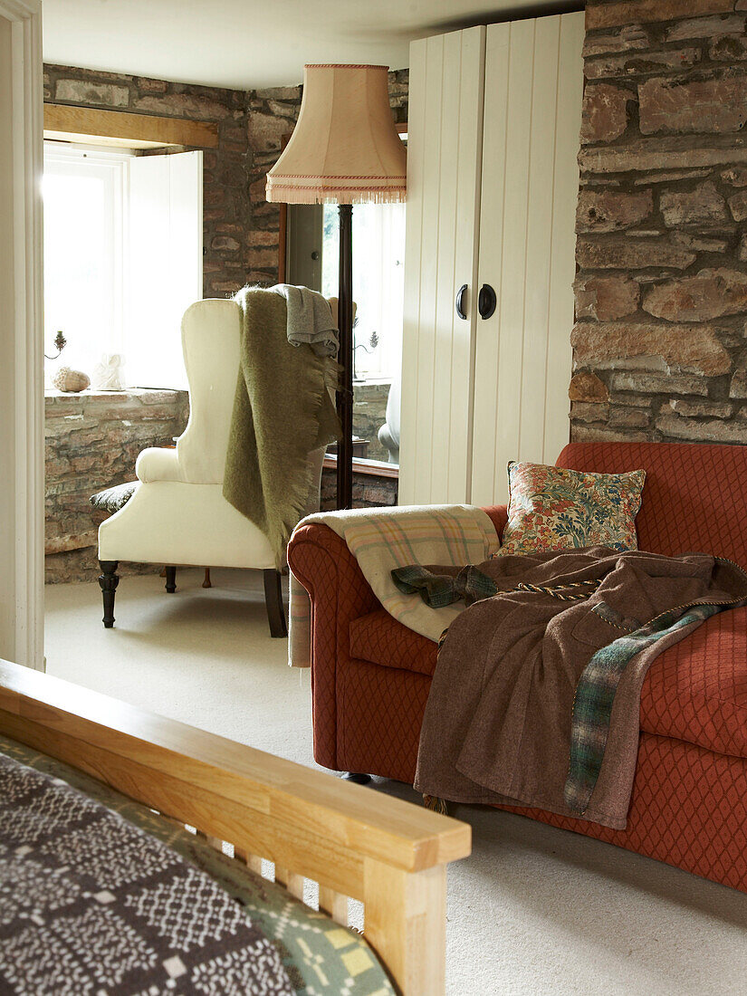 Bedroom with sofa and chairs and exposed stonework walls