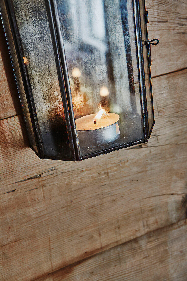 Wall light detail with tealight burning in Wooden cabin situated in the mountains of Sirdal, Norway