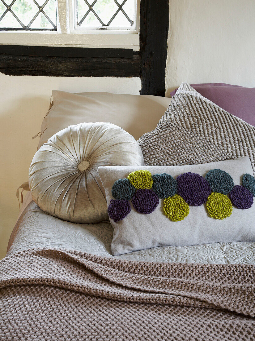Verschiedene Kissen auf einem Bett mit Decke in einem Cottage in Herefordshire, England, UK