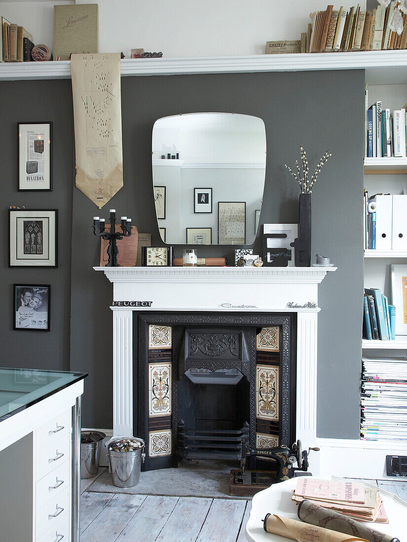 Vintage fireplace and mirror with books in muted grey living room of Winchester home, Hampshire, UK
