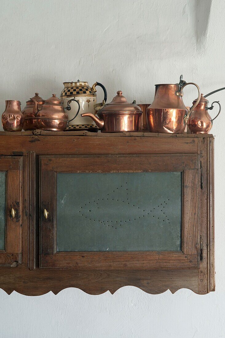 Collection of antique copper coffee pots on kitchen cupboard