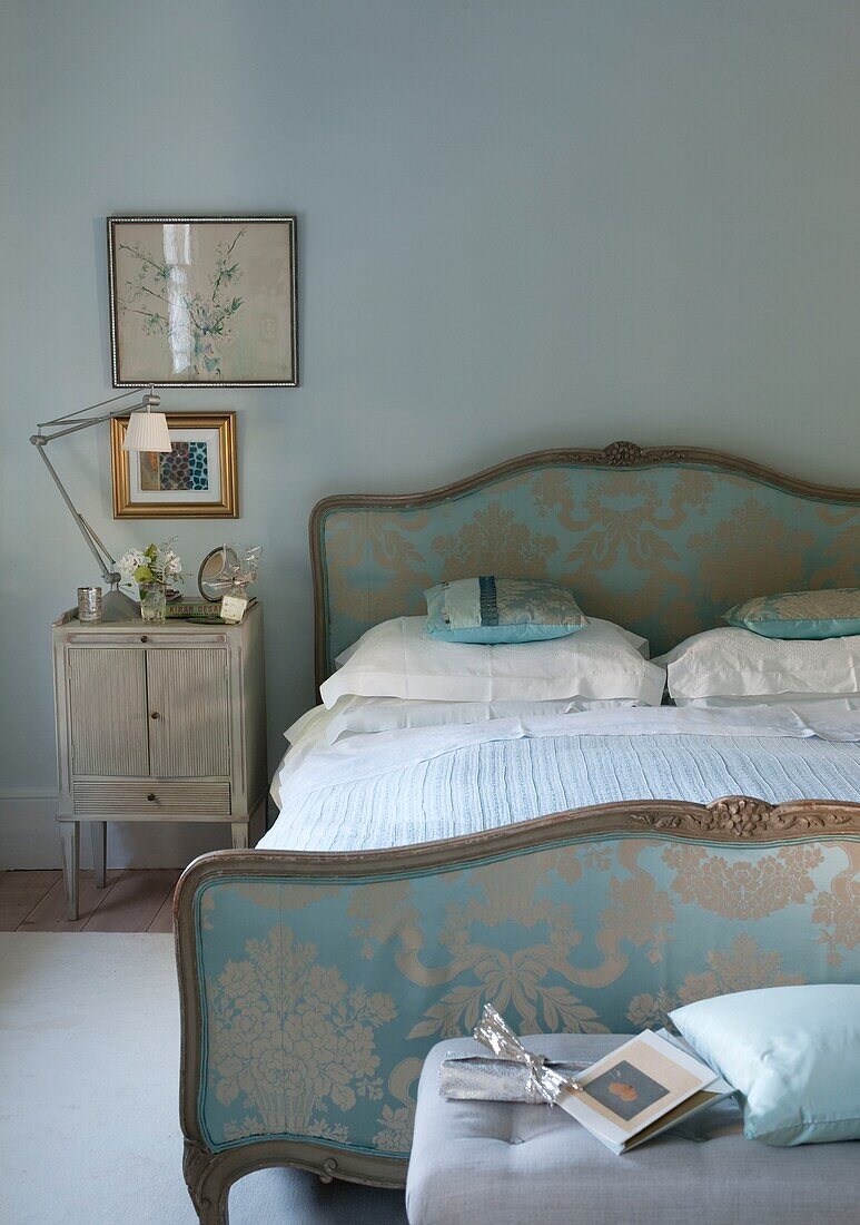 Silk Upholstered bed in pale blue bedroom with bedside table and lamp