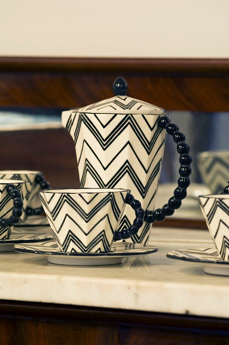 Porcelain tea pot and cups with zigzag pattern on the cupboard