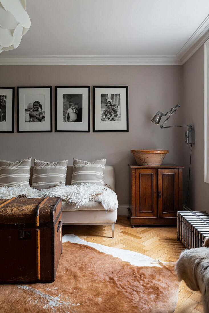 Black and white prints above sofa with sheepskins with vintage travelling trunk Woodbridge Suffolk UK