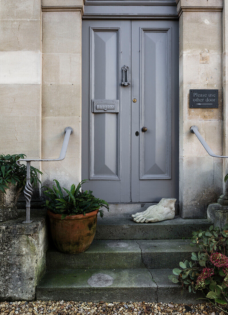 Pot plants and doorstop with grey double doors to Georgian home Somerset, UK