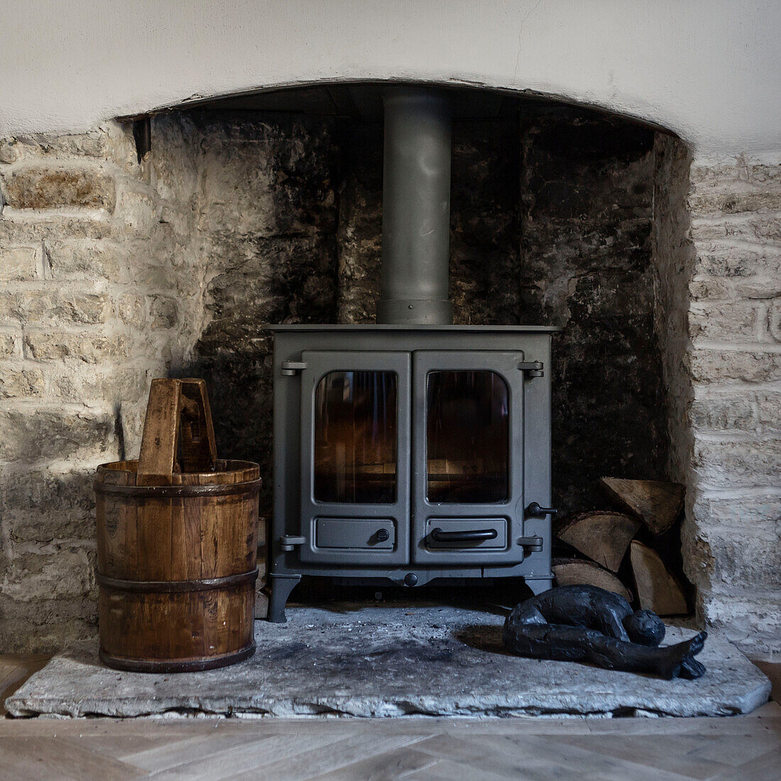 Woodburner with antique bucket in exposed stone fireplace Somerset home UK