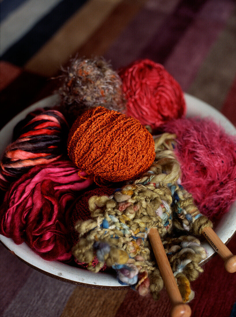 Balls of coloured wool in a bowl on a tabletop