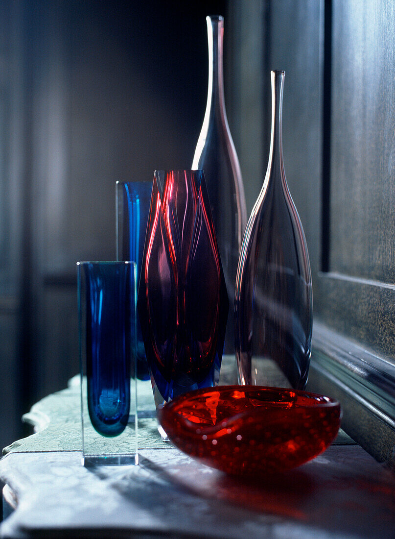 Display of collectable coloured glass vases bowls and bottles on a dresser in living room