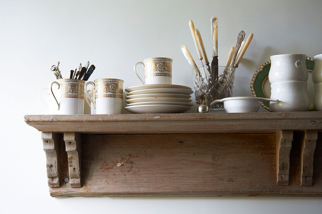 Vintage crockery and cutlery on shelf in Iden farmhouse, Rye, East Sussex, UK