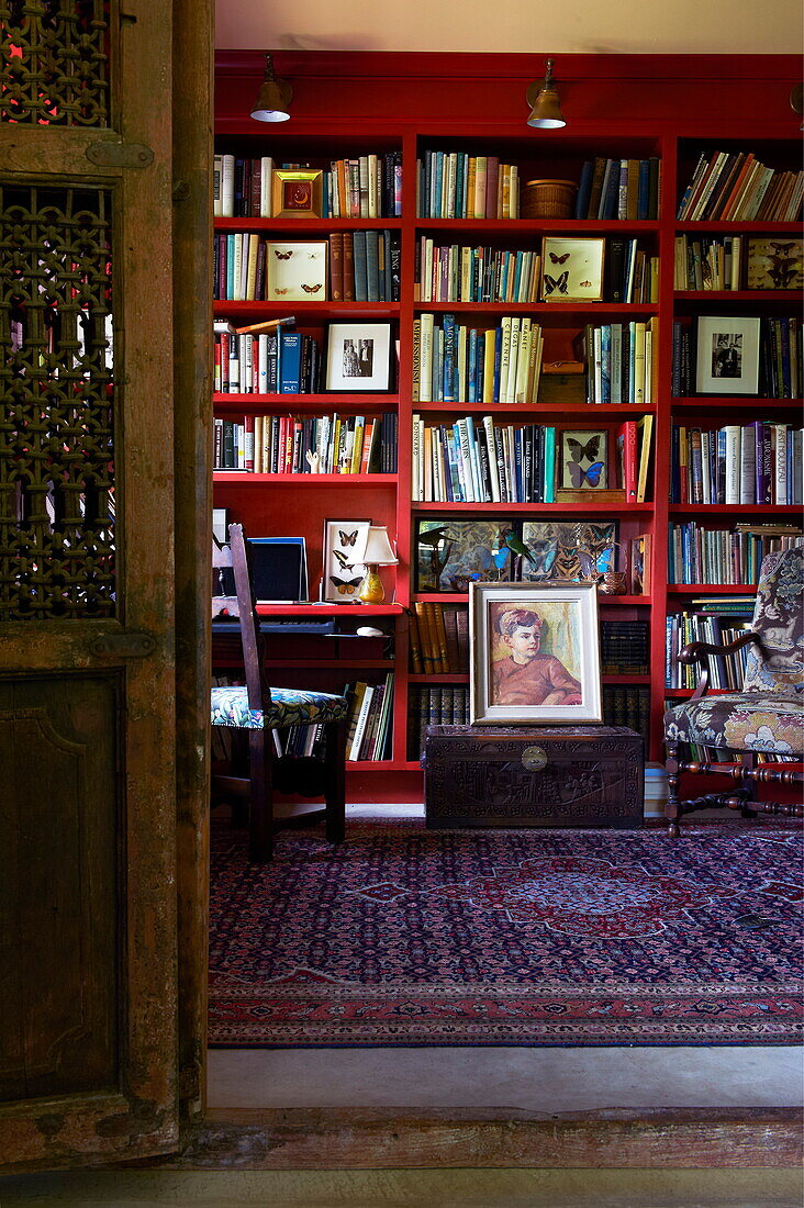 Red bookcase with patterned rug in Massachusetts home, New England, USA