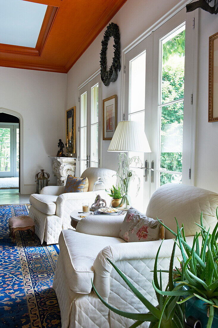 White upholstered matching armchairs at patio doors of Massachusetts home, New England, USA