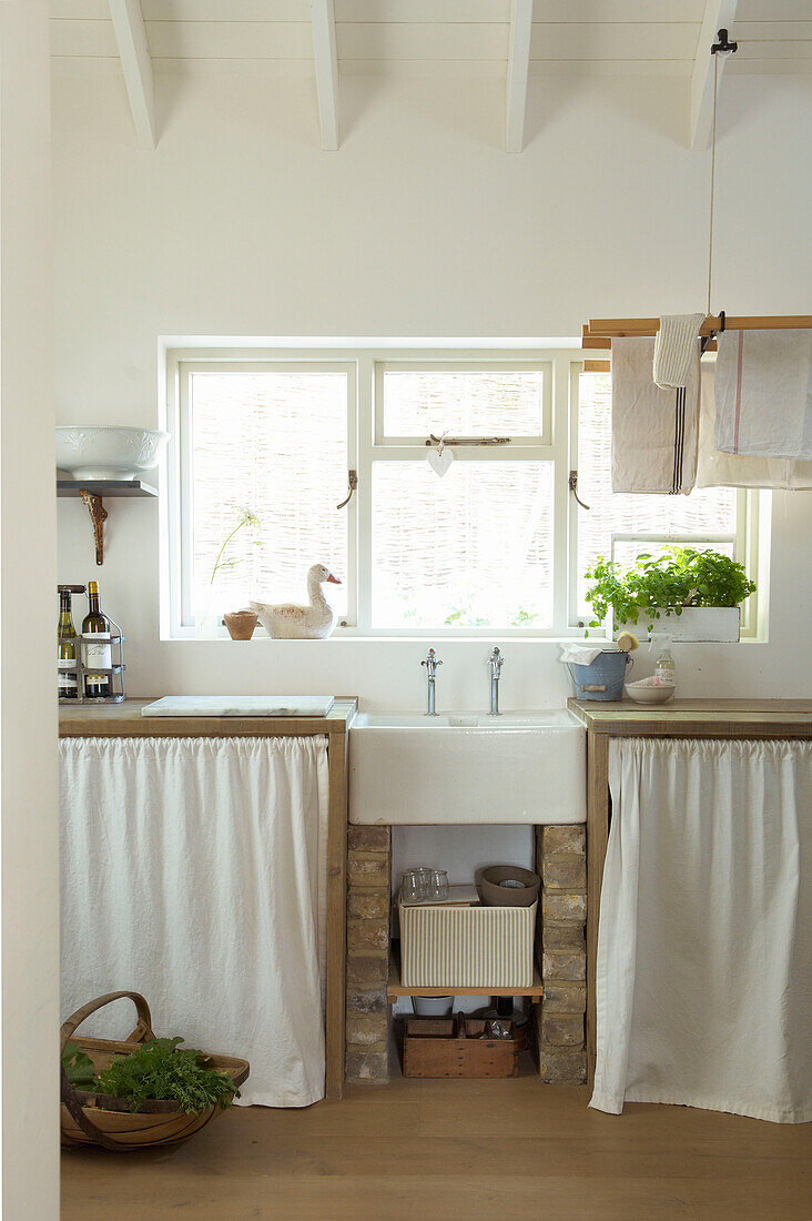 Curtained kitchen storage at window of Canterbury home England UK