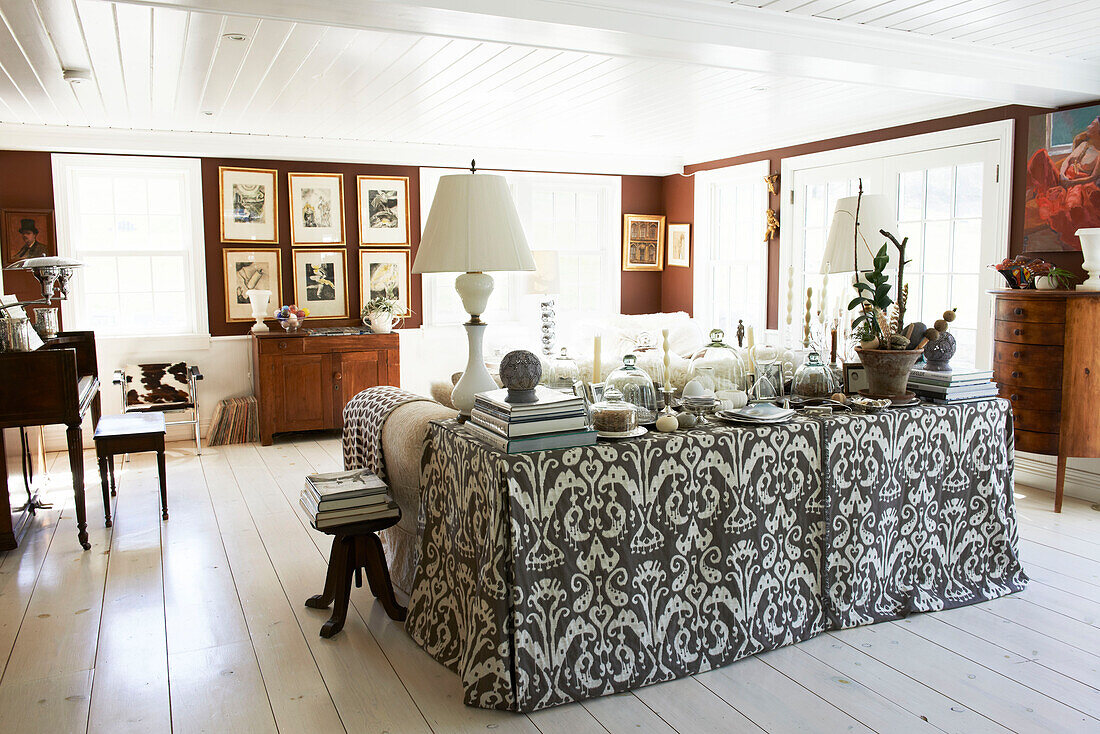 Lamps and artwork with ornaments on patterned fabric side table in Austerlitz living room, Columbia County, New York, United States