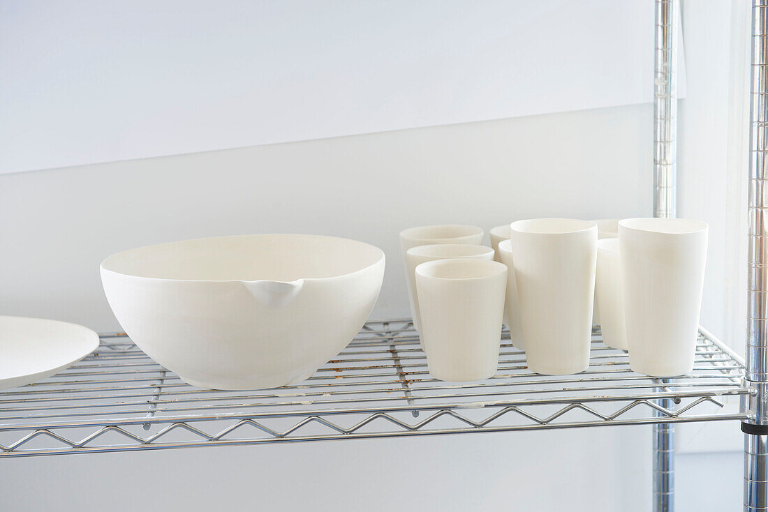 Ceramic cups and bowl on wire shelf in work studio, Austerlitz, Columbia County, New York, United States