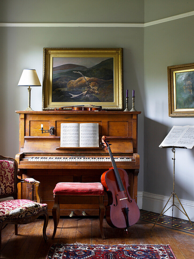 Cello leans on piano stool with sheet music in Hereford home, England, UK