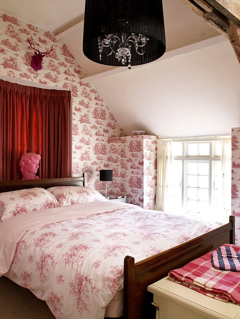 Toile de Jouy-Tapete und gemusterte Bettdecke auf einem Bett in einem walisischen Cottage, UK