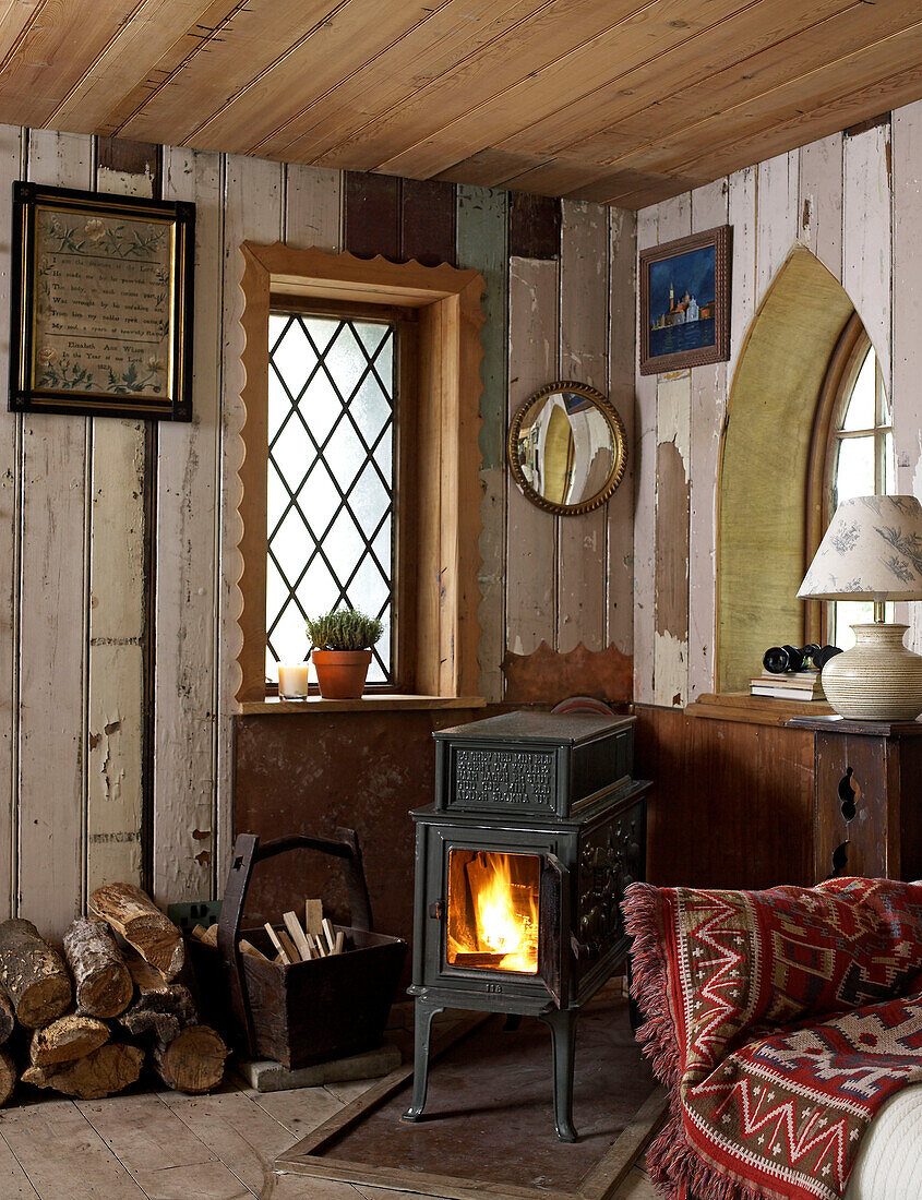 Wood burning stove and firewood in corner of converted Shropshire chapel England, UK