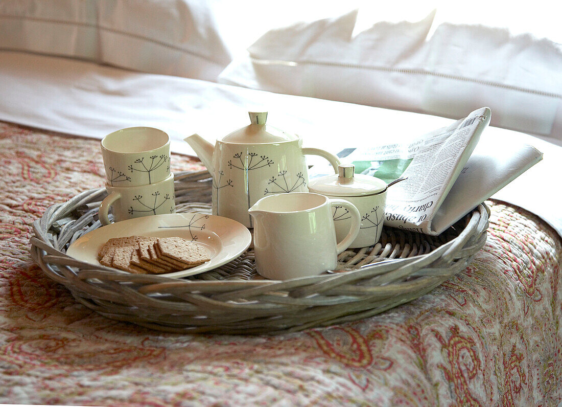 Teaset with biscuits and newspaper on bed in Shropshire chapel conversion England, UK