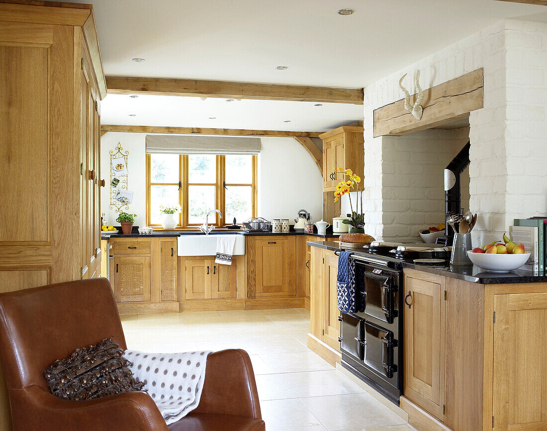 Brown leather armchair in open plan kitchen of Gloucestershire cottage England UK