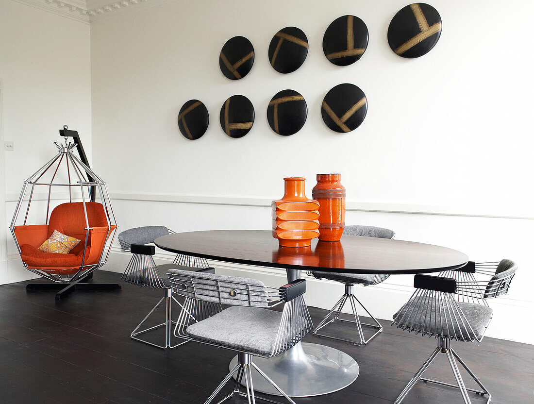 Modern art installation with orange hanging chair in dining room of contemporary Bath home Somerset England, UK