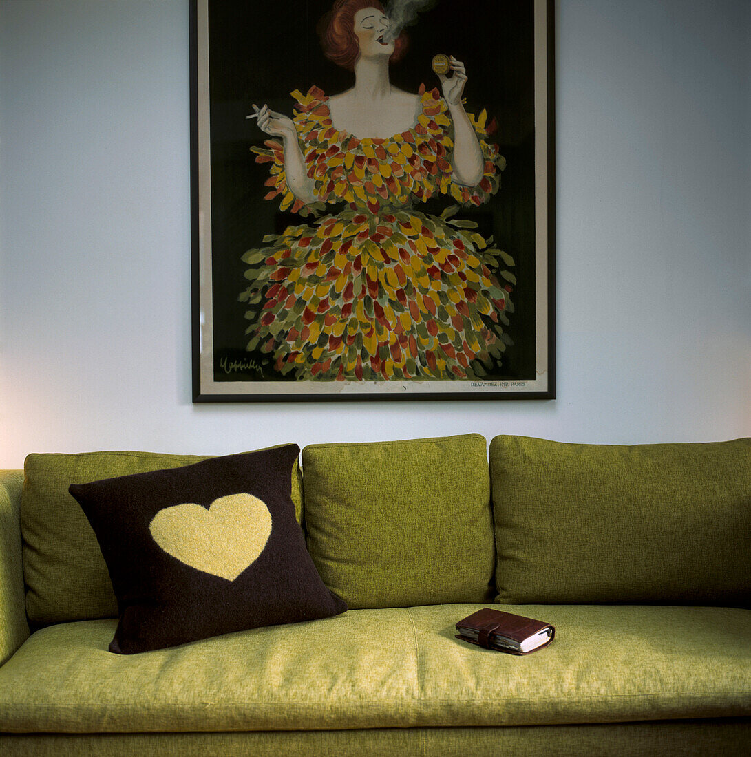 Green sofa against a white wall with vintage poster