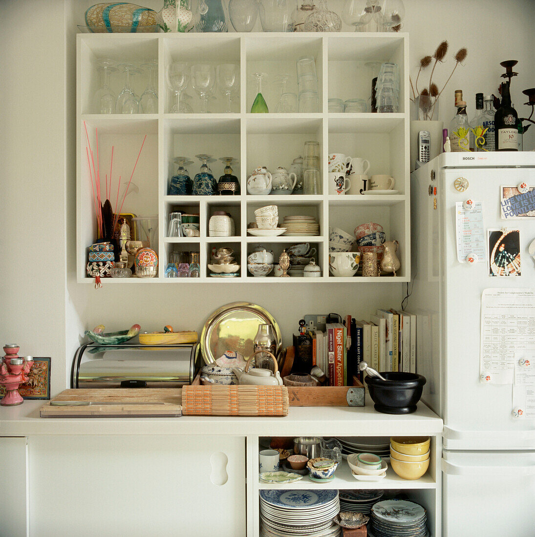 Open plan white kitchen units with crockery utensils glassware cook books and homeware on show