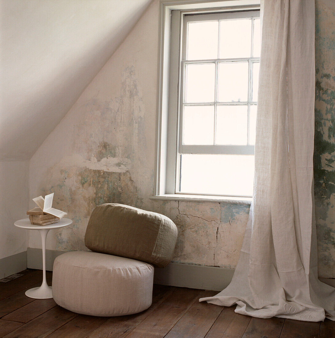 Loft room in need of decoration with linen curtains and floor cushions