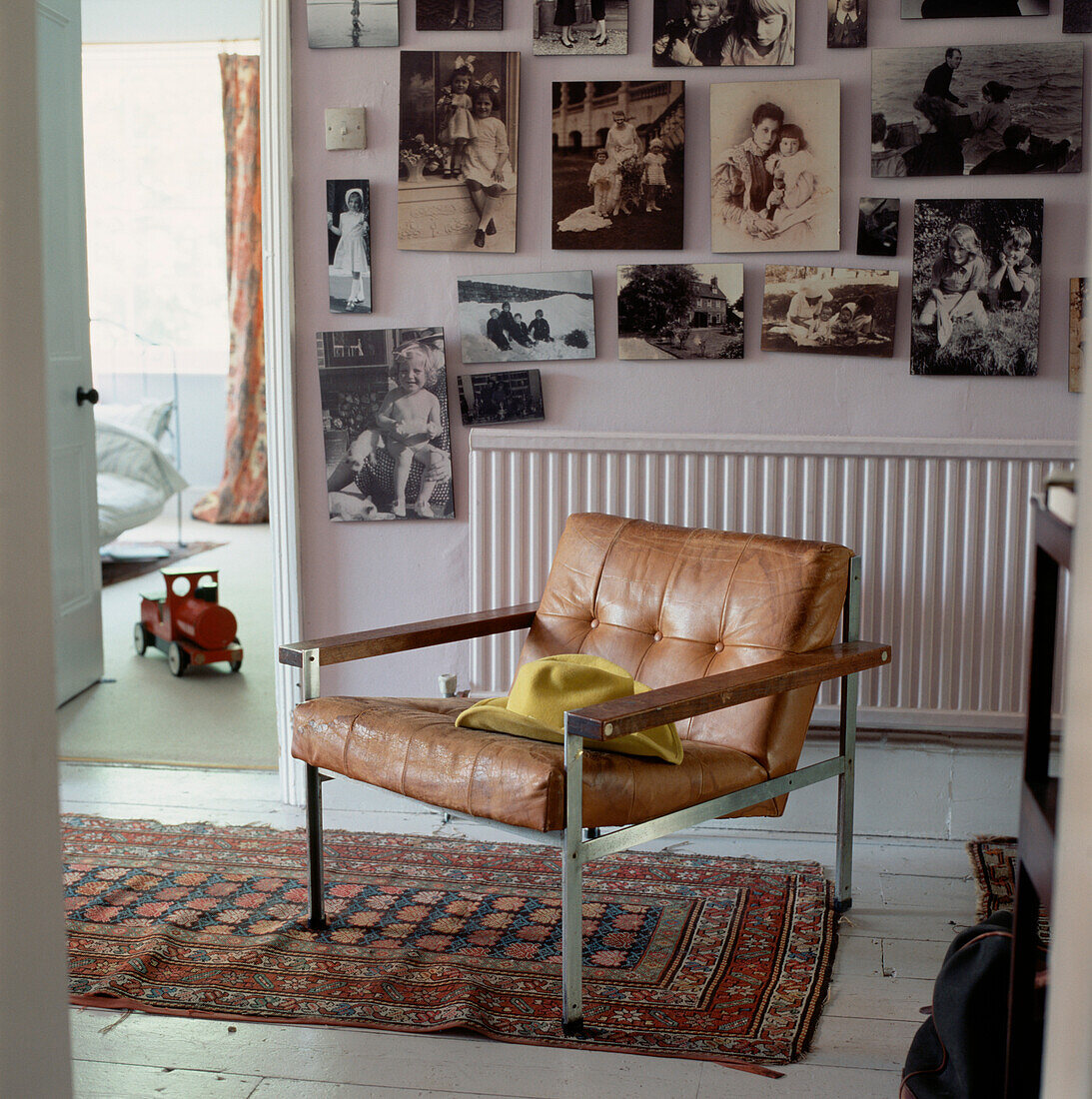 Display of old family black white and sepia photographs hung on a wall in an upstairs hallway with armchair and floor rugs