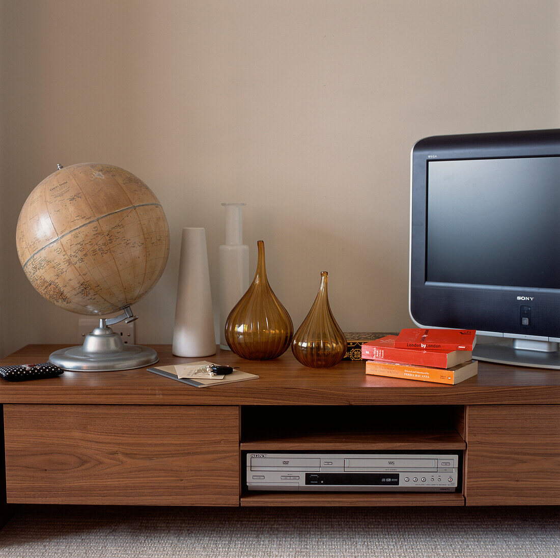 Moderner Fernseh- und DVD-Schrank aus Walnussholz im Wohnzimmer mit Glas- und Keramikvasen und Vintage-Globus