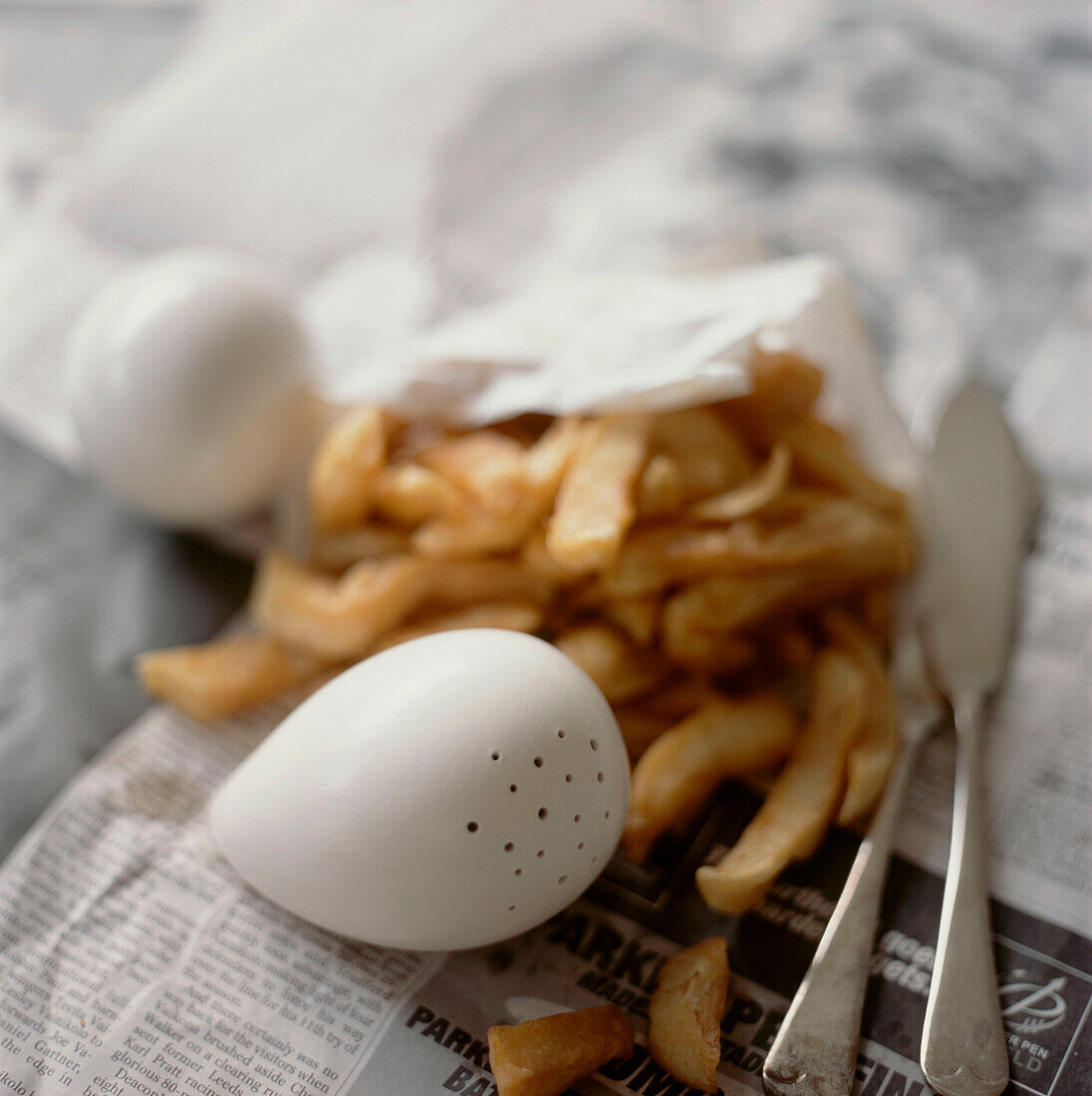 In Zeitung eingewickelte Pommes frites mit Salz- und Pfefferstreuer