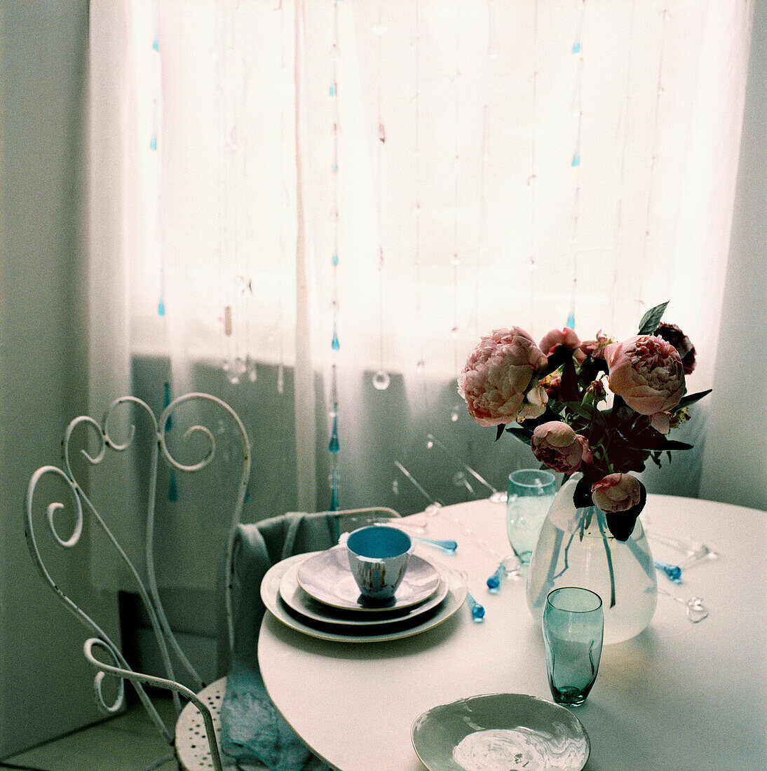Verschnörkelter Metall-Esszimmerstuhl mit rundem Esstisch und einer Blumenauslage