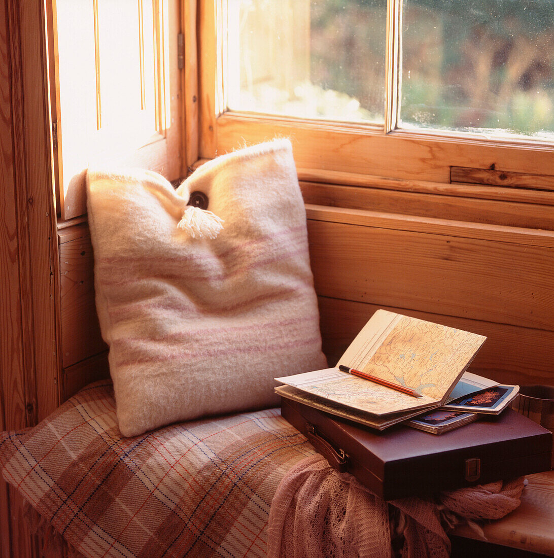Period style wood panelled window seat in cushion and wool blanket and reading material