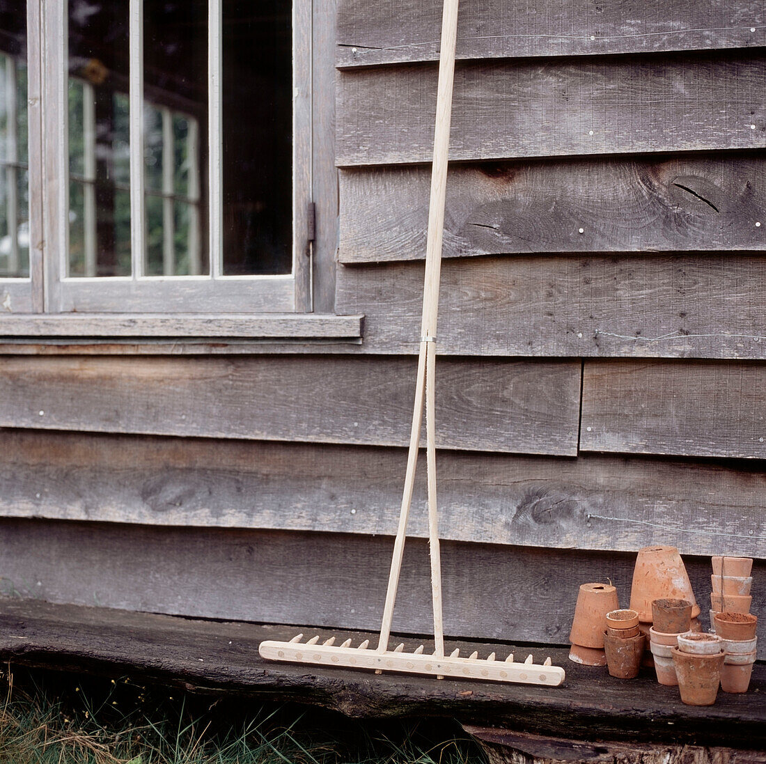 Detail of weather boarded house and gardening equipment