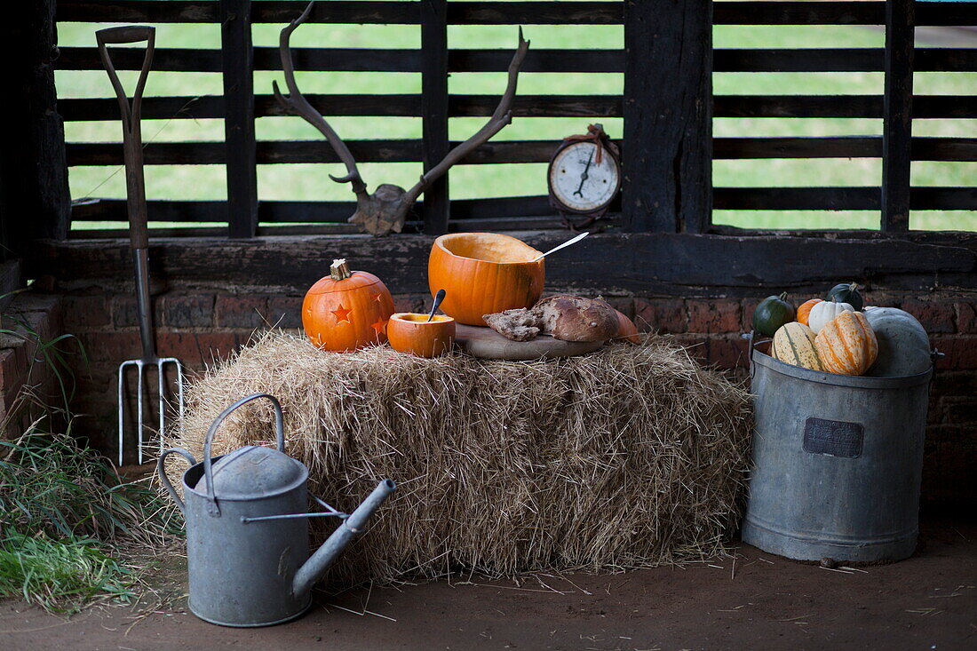 Pumpkins and hay bales in rustic barn interior, United Kingdom