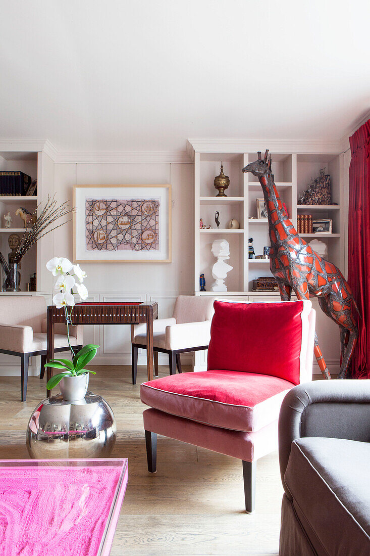 Red velvet chair with large giraffe statue in living room in contemporary London home England UK
