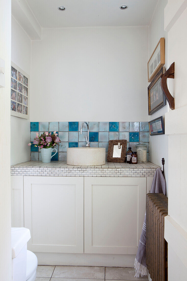 Rundes Waschbecken mit blau gefliester Spritzwand im Badezimmer eines Landhauses in Surrey, England UK