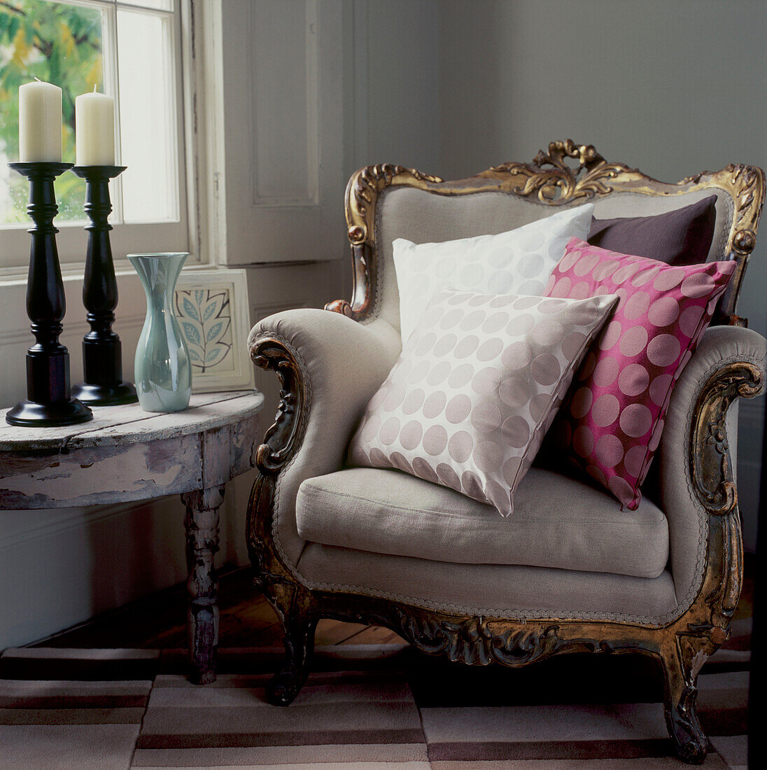 Decorative upholstered armchair nest to a window in a corner of a living room with cushions