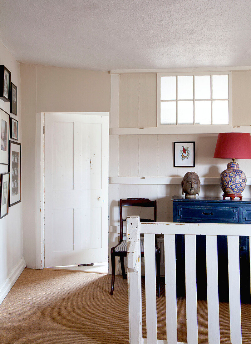 Antiker Stuhl und blau gestrichenes Sideboard mit an der Wand befestigten Fotografien im Eingangsbereich eines Hauses in Großbritannien