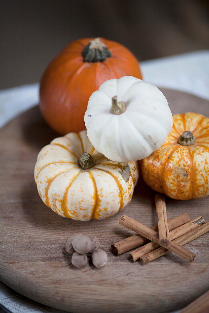 Pumpkins and cinnamon stick on chopping board in rustic interior, United Kingdom