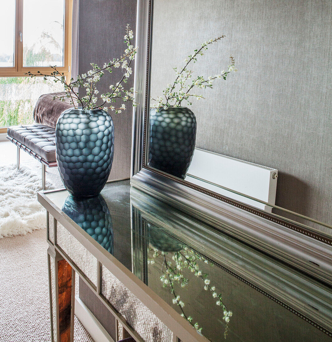 Cut flowers in blue glass vase with mirror on side unit in Lakes home, England, UK