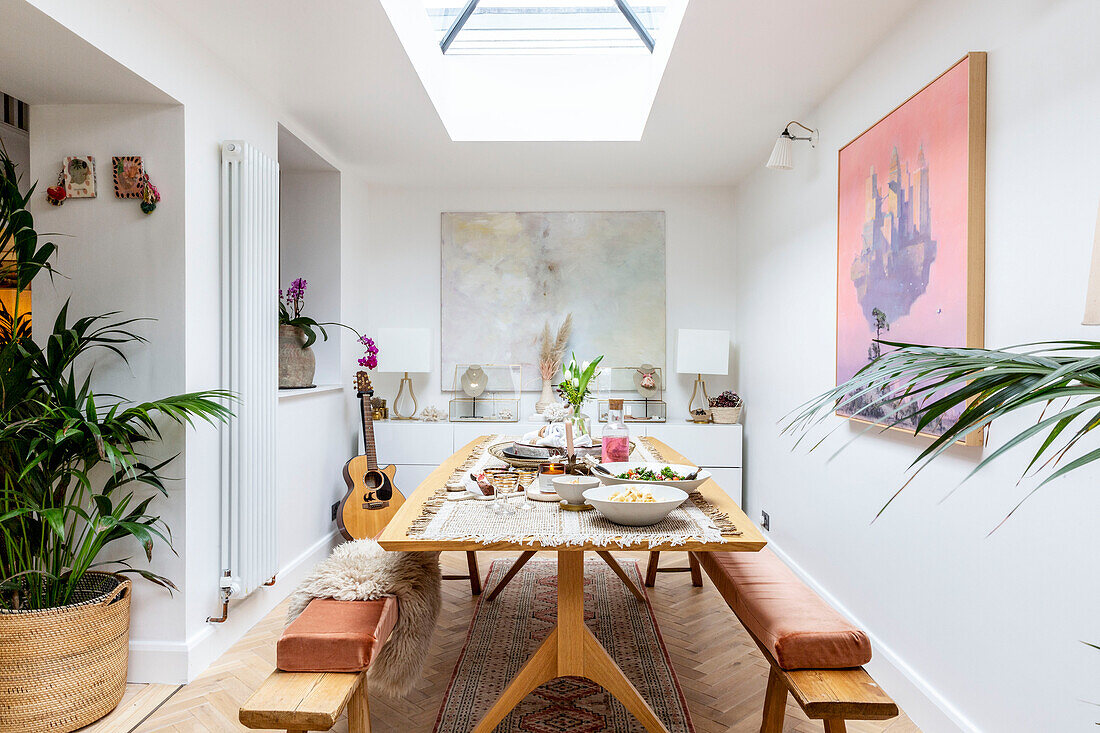 Bench seats and table below skylight in dining room extension of Devon cottage