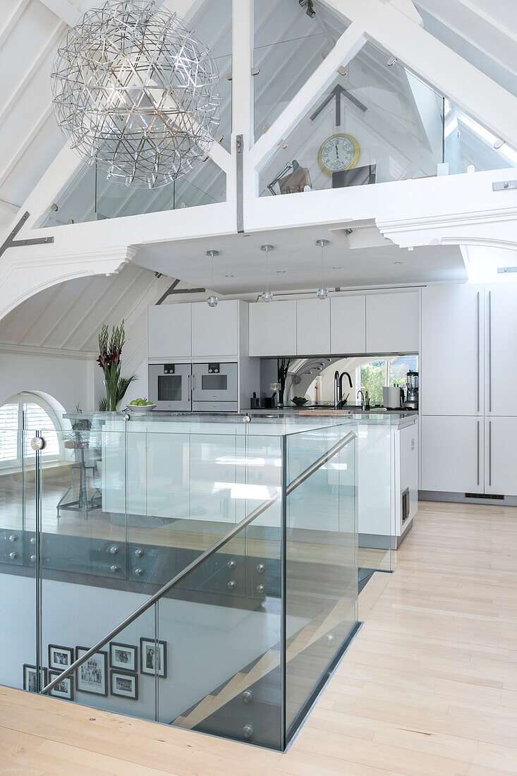 Open plan kitchen with polished concrete surfaces and glass banister in converted London courthouse UK