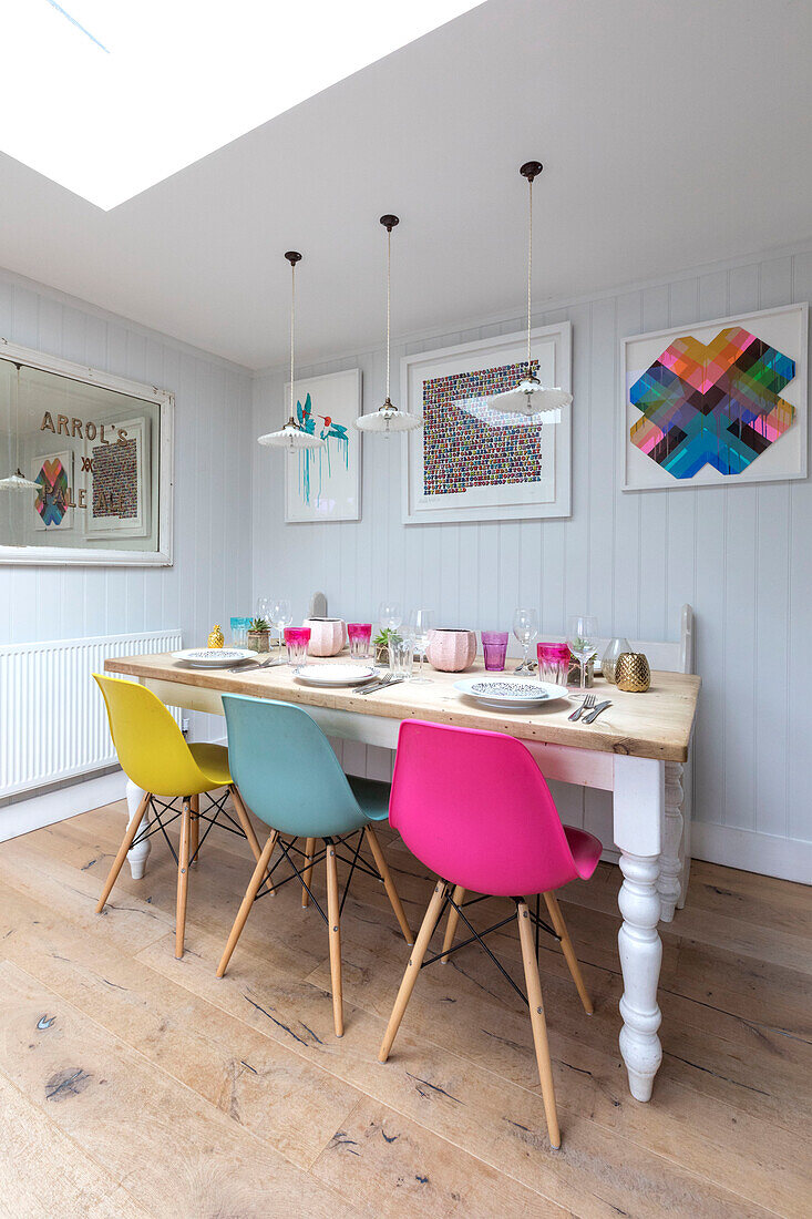 Esstisch aus altem Holz mit farbenfrohen Stühlen in einem Cottage in Guildford, Surrey, Großbritannien