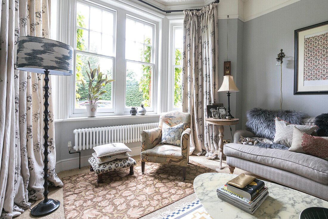 Polstersessel und Fußbank im Erker mit Sofa und Lampen in einem Haus in Guildford, Surrey, Großbritannien